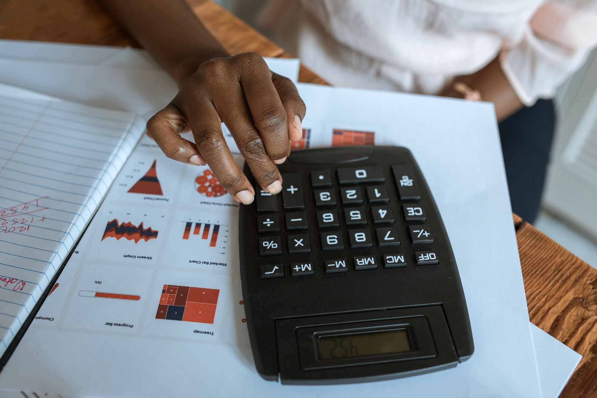 Person reviewing charts and making calculations with a desk calculator