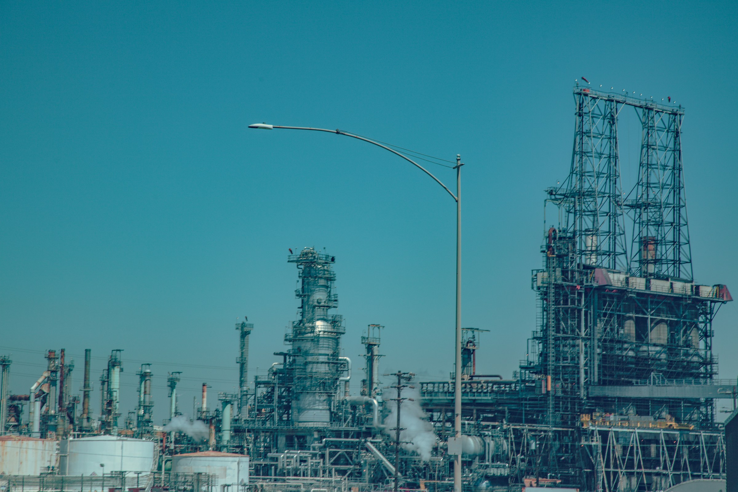 Oil refinery processing towers and pipework under a blue sky