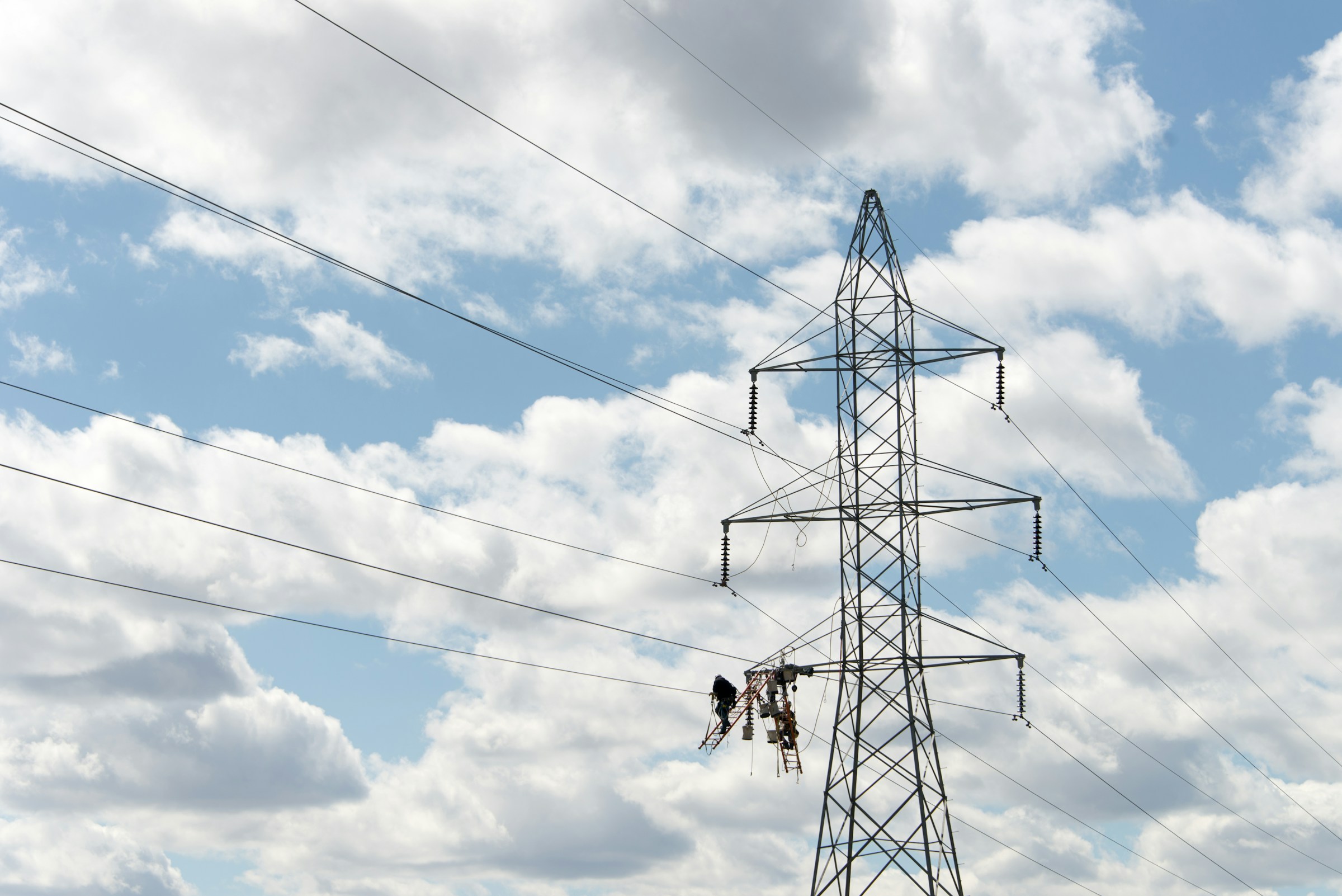 Power transmission tower with lineworkers maintaining electrical infrastructure