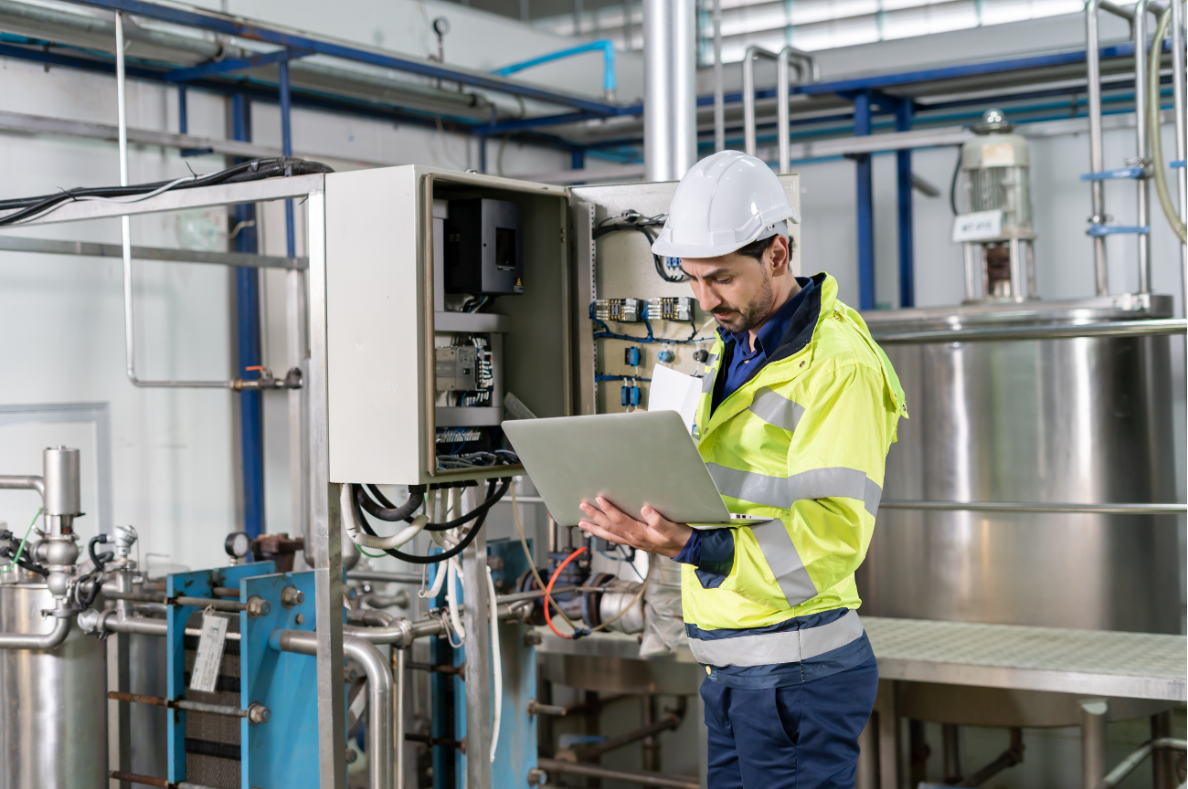 A technician inspecting industrial equipment with a laptop