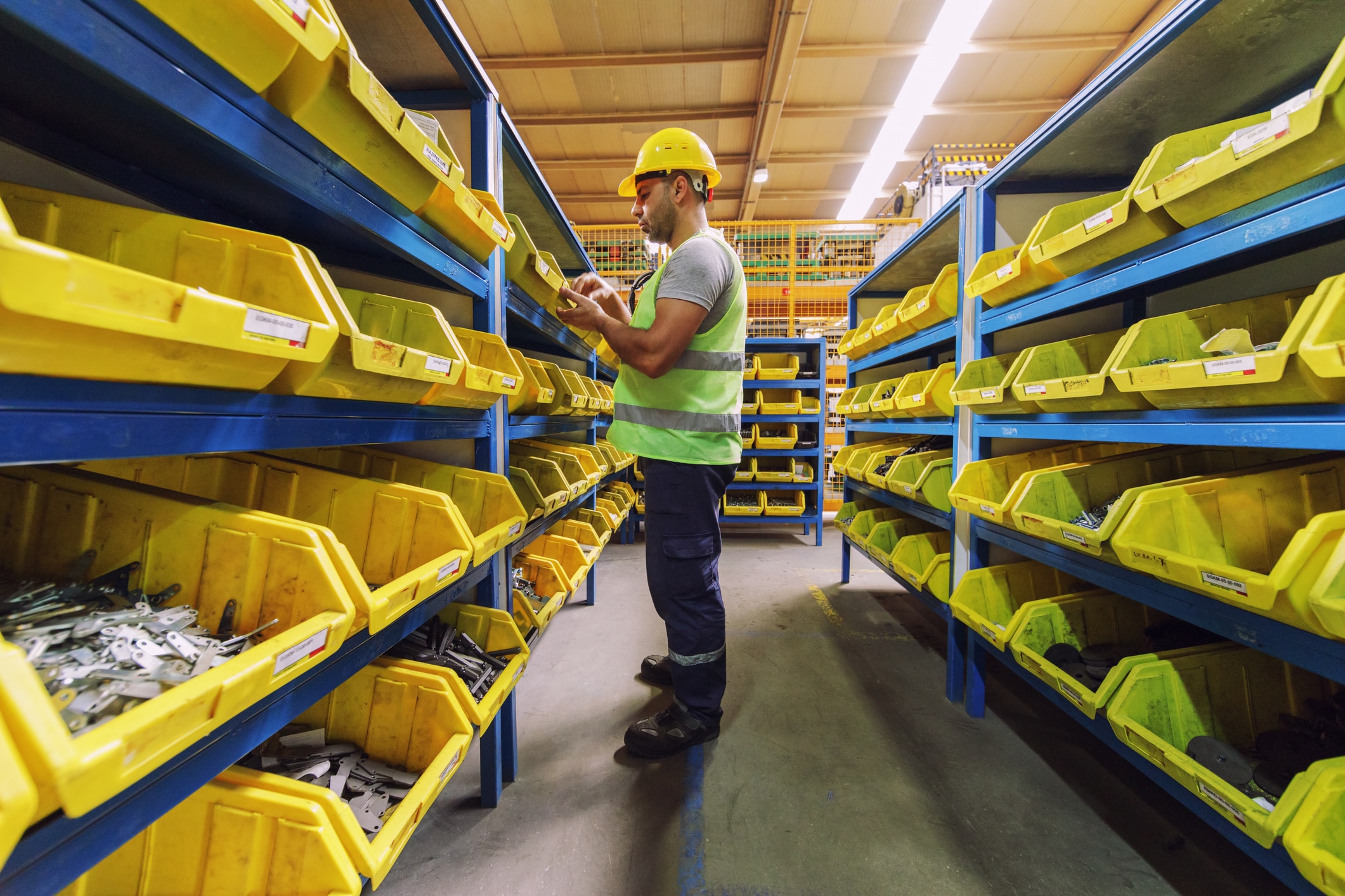An employee reviewing parts stored in yellow bins